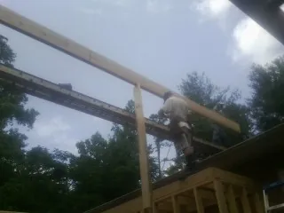 Carpenter setting a ridge beam over a new addition frame — Ice Dam Removal by Roofing Brothers in Cadillac