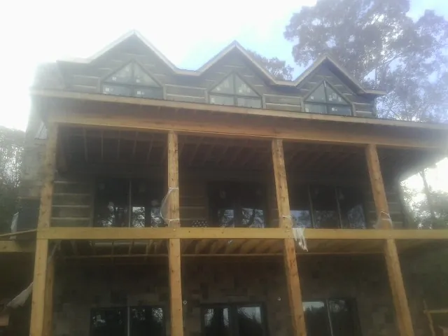 Dormers and porch framing on a large log home under construction — Roof Coating work by our crew in Cadillac