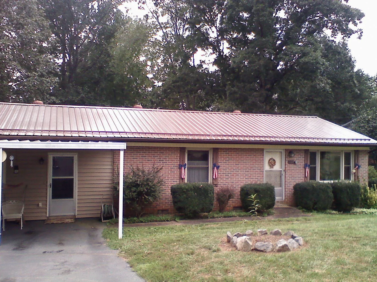 Bronze metal roof and carport on a brick ranch home — Roof Repair work by our crew in Cadillac